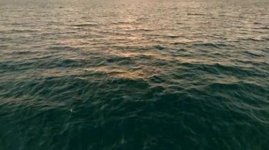 Büyüleyici deniz manzaralarını, sinematik dronumuzun esrarengiz deniz manzarasını ve büyüleyici bulutlu bir günbatımında dalgaların dokusunu sergilerken tecrübe edin..