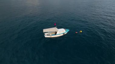 Denizin canlı renklerinde bir neşe kaynağı. Sinematik insansız hava aracımız beyaz ve mavi renkte bir balıkçı teknesi sergiliyor. Görkemli bir Akdeniz 'in arka planında sualtı balıkçılığıyla meşgul.