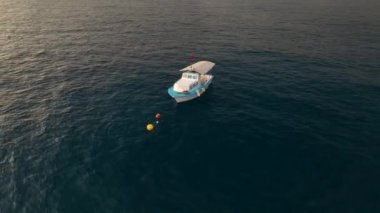 Sinematik dronumuz beyaz ve mavi renklerle boyanmış bir balıkçı teknesini yakalar ve arka planda sualtı balıkçılığının büyüleyici görüntüsünü seyredin.