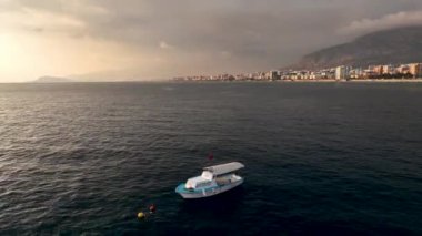 Ufkun dinginliğinin tadını çıkarın. Sinematik dronumuz beyaz ve mavi renkte bir balıkçı teknesini filme alıyor. Akdeniz alacakaranlığının dingin atmosferinde sualtı balıkçılığıyla meşgul..