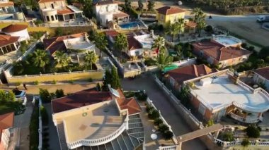 Profesyonel dronumuz sizi sinematik bir yolculuğa çıkarırken bu villa kompleksinin ebedi güzelliğini tecrübe edin. Büyüleyici mimariyi keşfet, davet havuzu, yemyeşil bahçeler, ve sakin teras..