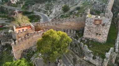 İnsansız hava aracı, yüzyıllık evlerin üzerinde yükselen tarihi kalede seyreden üstü açık arabayı yakalarken sinematik bir yolculuk yaşayın.