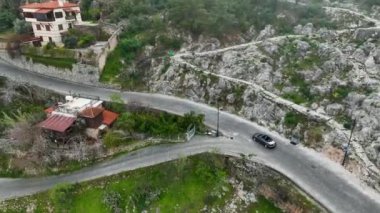 Kıyı yolculuğunun tadını çıkarın. İnsansız hava aracı, yüzyıllardır yemyeşil evlerle çevrili antik kalede üstü açık arabayı takip ediyor.