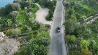 Türkiye 'nin Alanya kentinde heyecan verici bir hava macerasına atlayın. İnsansız hava aracı, antik kalenin kıvrımlarında ve dönüşlerinde uçan üstü açık bir arabayı takip ediyor.