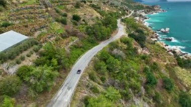 Bereketli tarım alanlarıyla çevrili kayalık sahil şeridi boyunca yayılan sebzeler ve meyve tarlalarıyla. Bulutlu hava, güçlü gök mavisi dalgalarıyla sahneye dram katıyor..