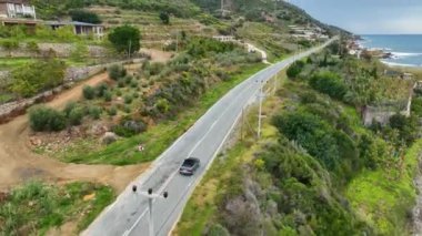 İnsansız hava aracı manzaralı sahil şeridinde süzülen üstü açık bir arabayı yakalarken deniz kıyısındaki zenginliğin tadını çıkarın. Geniş sebzeleri ve geniş meyve tarlaları olan pitoresk tarım arazilerine hayranlık duyun.