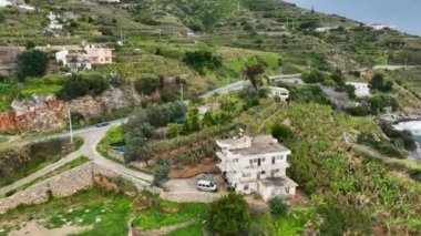 İnsansız hava aracı, asfalt yolda bir tarım bölgesinin kayalık kıyı şeridi boyunca uzanan manzaralı yolu yakalar. Yeşillik sebzelere ve meyve tarlalarına hayran kaldım.