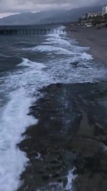 Bu dikey videoda kıyı manzarasının ihtişamını keşfedin. Büyüleyici sisli atmosferi ve renklerin dramatik etkileşimini tecrübe edin..