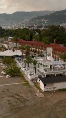 Kendinizi bu çarpıcı dikey videoda yakalanan fırtınadan sonra sahilin kenarındaki bir kafenin huzurlu güzelliğine daldırın. Uçsuz bucaksız havuz cazibemi artırıyor..