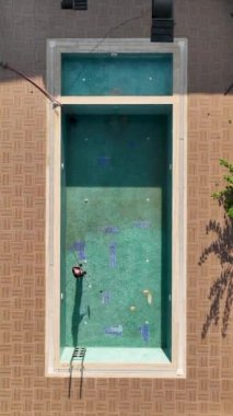 Bu dikey videoda kirli bir havuzun el değmemiş bir cennete dönüşmesini deneyimleyin. Havuzu titizlikle temizleyen yetenekli işçiyi izleyin nefes kesen bir deniz manzarasına karşı