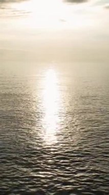 Deniz üzerinde büyüleyici sisli bir günbatımının mistik atmosferini deneyimlemek, bu büyüleyici dikey videoda suyun sihirli dokusunu ortaya çıkarmak..