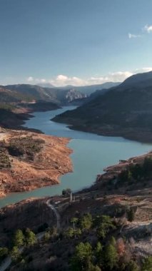 Kristal berrak suların kayalık araziyi oyduğu bir nehrin ihtişamına dalın. Bu dikey video dinamik manzarayı ve ham gücü yakalar ve nefes kesici bir canlı yapar.