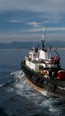 Bir römorkör ve bir gemi arasındaki kusursuz koordinasyona tanık olun. Denizin sorunsuz işlediğinden emin olmak için senkronize çalışıyorlar. Bu dikey video gerekli hassasiyet ve takım çalışmasını gösterir