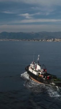 Mavi suları zarifçe kesen bir deniz römorkörünün zarafetine tanık olun. Bu dikey video, teknelerin çevikliğini ve denizin büyüleyici güzelliğini gösteriyor..