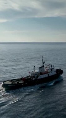 Büyüleyici bir yolculuğa çıkın. Bir römorkör, engin mavi alanda sorunsuzca yol alır. Bu dikey video denizin engin güzelliğini ve huzurunu yakalar..