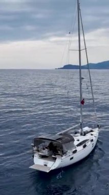 Bu dikey videoda beyaz bir yat limana dönerken kış yat inzivasına katılın. Yatın güzelliğine ve inceliğine tanık olun. Kış arkaplanına karşı..