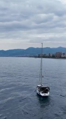 Bu dikey videoda, muhteşem derin mavi denizdeki limana doğru yavaş bir geçiş yapan bir yat sükunetine dalın. Huzurlu ve rahatlatıcı atmosferin tadını çıkar..