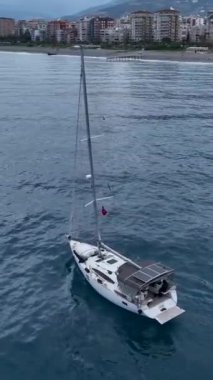 Bu dikey videoda bir yelkenlinin soluk kesen derin mavi denizdeki limana yavaş geçişi için havadaki dinginliği hissedin. Sinematik dron çekimlerinin tadını çıkarın. Anın sükunetini yakalayın..