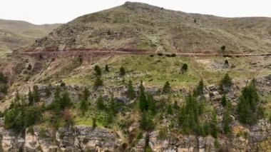 Görüntünün seyrekliğini hissedin. İHA, otlayan bir koyun sürüsünün hava görüntüsünü yakalarken destansı dağ manzarasını sinematik olarak yakalıyor..