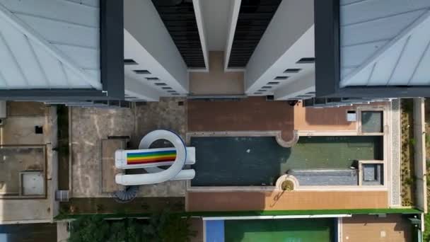 ドローンが予想される住宅団地の活気あるウォータースライドをキャプチャするように 空中の観点から爽快なスリルを体験してください — ストック動画