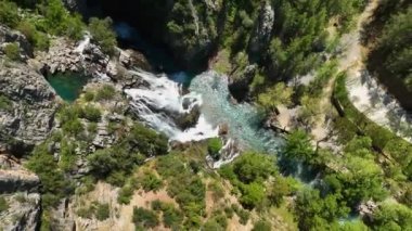 İlkbaharda etrafındaki ormanların canlı yeşillikleri arasında çağlayan güzelliği yakalayan dron, yukarıdan gelen fevkalade bir şelalenin hayranlık uyandırıcı manzarasını ele alın..