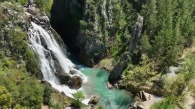 İnsansız hava aracı nefes kesen şelalenin hava keşfine çıkarken, parıldayan gök mavisi sularını ve el değmemiş beyaz köpüğü gözler önüne sererken güzelliğin doğasına tanık olun..