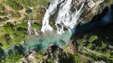 İHA 'nın sunduğu şelalenin gök mavisi duvağının havadan manzarasını zevkle seyret. Puslu atmosferi süsleyen prizmatik gökkuşaklarıyla taçlandırılmış..