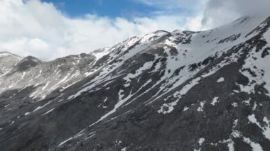 Kendinizi unutamayacağınız bir dağ deneyimine daldırın. İlkbaharın havadan bakış açısıyla görkemli zirveler, karlı zirvelerin sinematik çekimleri ve bulutların öptüğü manzaralar..