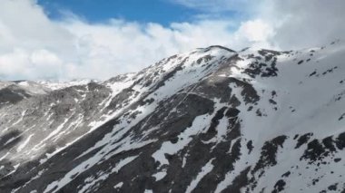Baharın başlarındaki Türk dağlarının nefes kesici güzelliğini deneyimleyin. İnsansız hava aracı bulutların arasında süzülerek, karla kaplı zirvelerin ve destansı manzaraların sinematik görüntülerini yakalıyor..