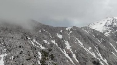 Yukarıdan bakıldığında bulutlarla kaplı dağların görkemli manzarasından ilham alın. Dağlık arazinin engebeli güzelliğini ve ihtişamını keşfedin..