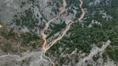 Hava görüntüleri, dramatik dağlar ve etrafındaki bulutların ruhani güzelliği arasındaki uyumlu etkileşimi gösteriyor..