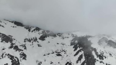 Dağların ve bulutların hayranlık uyandıran güzelliğine dikkatle bakın. İHA gökyüzünde süzülüyor, sinematik bir hava manzarası yakalıyor..