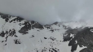 İnsansız hava aracı yukarıdan nefes kesici etkileşimlerini yakalarken dağların ve bulutların ahenkli senfonisini deneyimleyin..