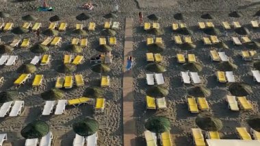 İnsansız hava aracı, sakin ve davetkar Akdeniz sahillerinde huzur içinde dinlenen terk edilmiş plaj şezlonglarının havadan görüntüsünü sergilerken yalnızlığın dinginliğini kucaklayın.