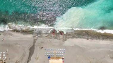 Sahildeki canlanmanın kuş bakışı görüntüsünü alın. İnsansız hava aracı, kayalık sahili değiştiren güçlü dalgacıların etkileyici görüntüsünü yakalıyor.