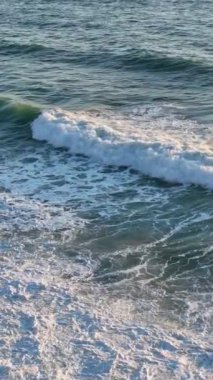 Fırtınalı bir denizin üzerinde ağır çekimde yapılan insansız hava aracının büyüleyici güzelliğini tecrübe edin. Dinamik beyaz köpük bu büyüleyici dikey videoda gök mavisi sularla buluşur..
