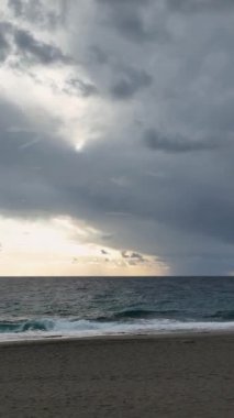 Sahildeki bir rüya sahnesine adım atın. Dikey görüntüde sunulan en güzel bulutlu gün batımına tanık olun..