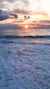 Dalgaların dansını izleyin ve büyüleyici dokusunu büyüleyici bir günbatımının arka planına karşı gösterin..