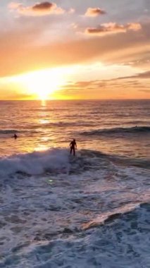 İzlediğiniz gibi mükemmel dalgayı yakalayın sörfçüler zarif bir şekilde gün batımına doğru sürerler, bu dikey videoda nefes kesici sörf sahneleri yakalarlar..