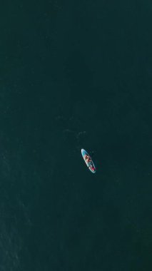 Gün batımı yansımaları sırasında suda sürüklenen bir çiftin dinginliğini hissedin büyüleyici bir hava perspektifinden çekilen.