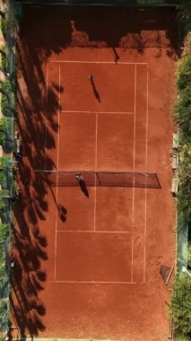 Oyuncular avuçlarıyla çevrili bir tenis kortunda rekabet ederken sakin bir ortama geri çekiliyorlar ve yukarıdan sakinleştirici bir manzara sağlıyorlar..