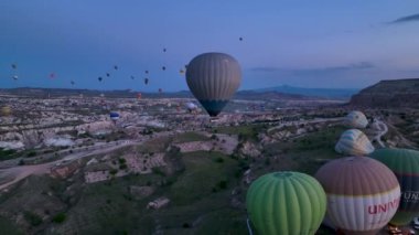 hot air balloons fly over the mountainous landscape of Cappadocia, Turkey. Aerial view