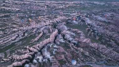 hot air balloons fly over the mountainous landscape of Cappadocia, Turkey. Aerial view