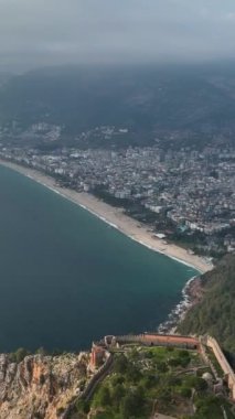 Bulutlu Alanya üzerinde keyifli bir hava macerasına atlayın, bu dikey videoda Akdeniz kıyısındaki antik kaleyi ve otantik çevresini keşfedin..