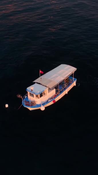 釣り船として黄金の時間を受け入れる日没時に帆 この垂直ビデオで海の表面に太陽光の反射ダンスと — ストック動画