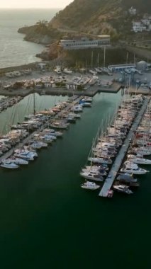 Bu dikey videoda güzel bir günbatımında Alanyas limanında demirlemiş yatların sinematik görüntüsünü yakalayın..
