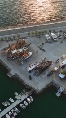 Gün batımında Alanyas limanının güzelliğine hayret edin, muhteşem yatlar rıhtımları kaplıyor, yukarıdan çekilen bu dikey videoda.