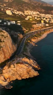 Bu dikey videoda, deniz kenarındaki tünele giden bir yolun havadan görüntüsüne tanıklık ederken heyecan verici bir sahil yolu macerasına binin...