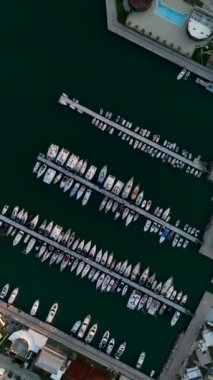 Gün batımında Alanyas limanının büyüleyici görüntüsüne şahit olurken huzurlu bir serenat yaşayın. Bu dikey videoda zarif yatlar cazibesine katkı sağlar..