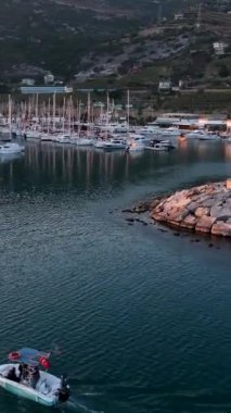 Günbatımında Alanyas limanında demirlemiş yatların dingin güzelliğini deneyimleyin, bu dikey videoda yukarıdan çekilen.